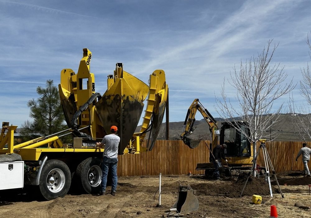 Man working controls on spade truck to plant a large tree
